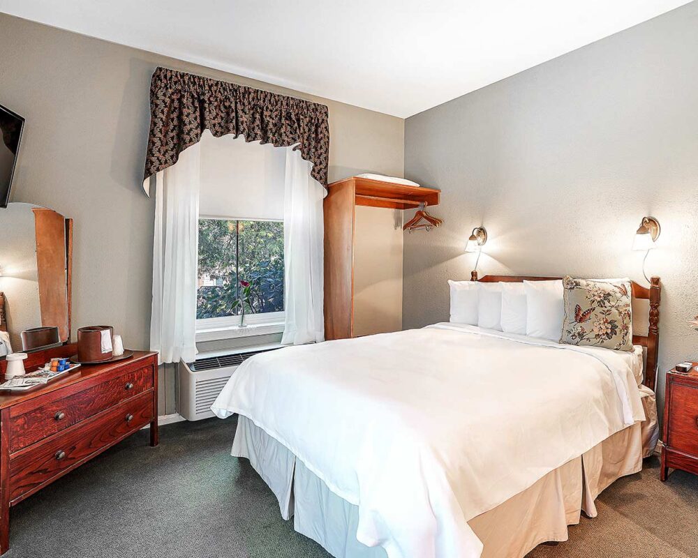 JLOD - Standard Queen Room 1 A view of the standard Queen room at theJulian Lodge with a bed, vanity and window.